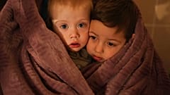 The children of medical workers warm themselves in a blanket as they wait for their relatives in a hospital in Mariupol, Ukraine, Friday, 4 March, 2022