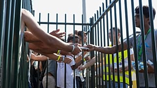 Люди в переполненном центре для мигрантов в Тер-Апеле на севере Нидерландов тянутся за мороженым в жаркий день. 