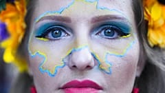 A woman made up with the outline of a map of Ukraine on her face celebrates Ukrainian Independence Day in Berlin, Germany, Wednesday, Aug. 24, 2022.
