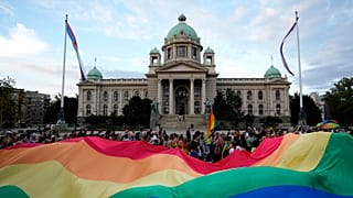 Participants carry large rainbow flag in front of the parliament building as they take part in the annual LGBT pride march in Belgrade, 19 September 2021