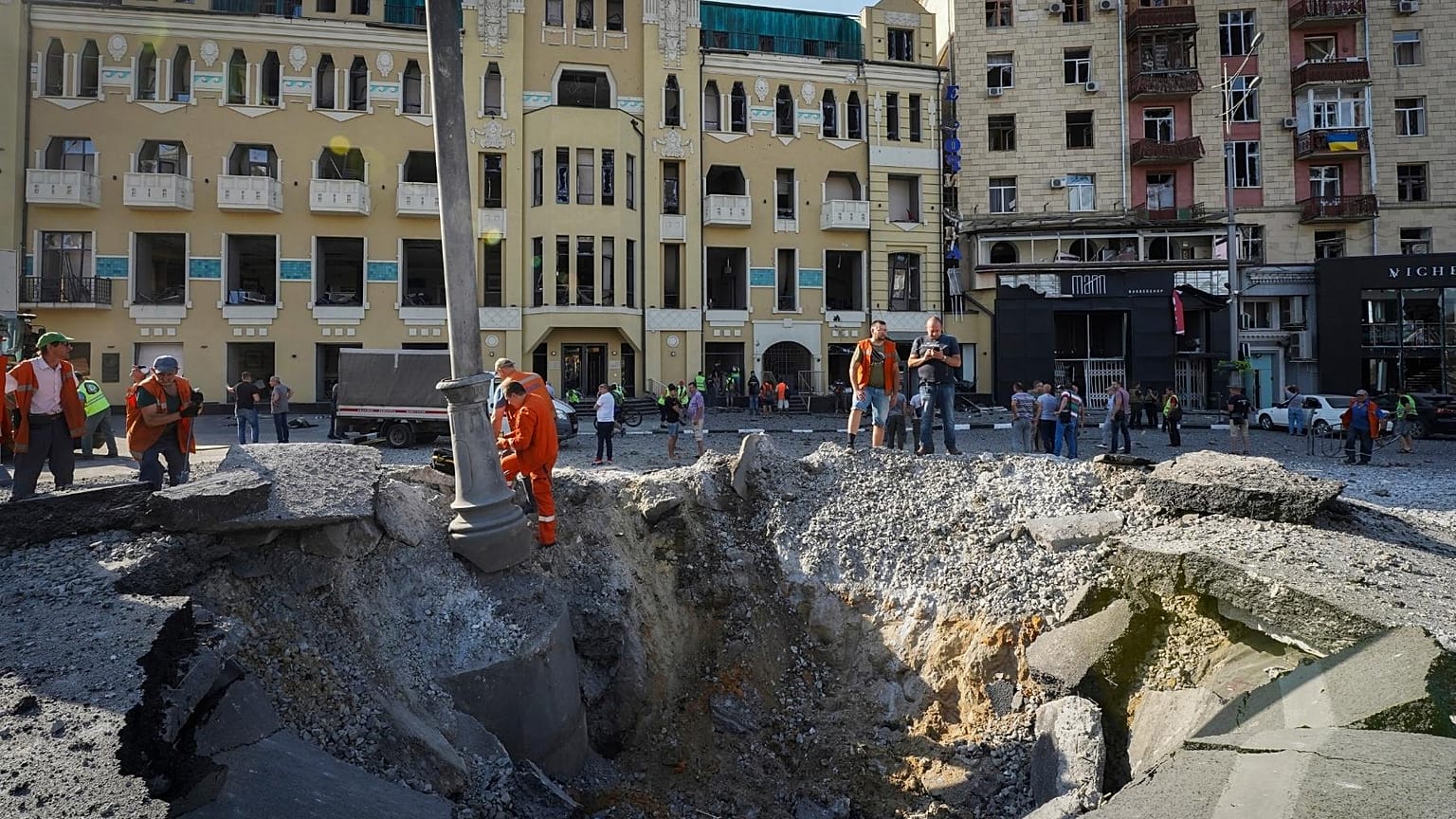 A view of a crater from a night Russian rocket attack, near to damaged buildings in downtown Kharkiv, Ukraine, Saturday, Aug. 27, 2022.