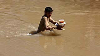 Aşırı yağışların neden olduğu sel nedeniyle evinden kaçan ve kendilerine verilen yemeği taşımaya çalışan bir çocuk.  Peşaver / Pakistan