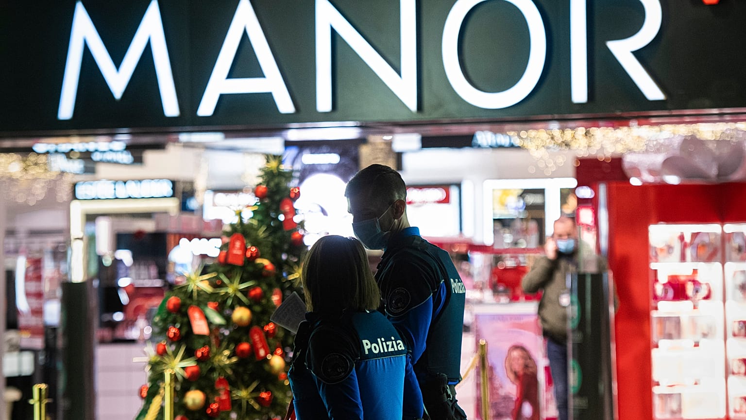 Police walk near the area where the stabbing occurred in a department store in Lugano.