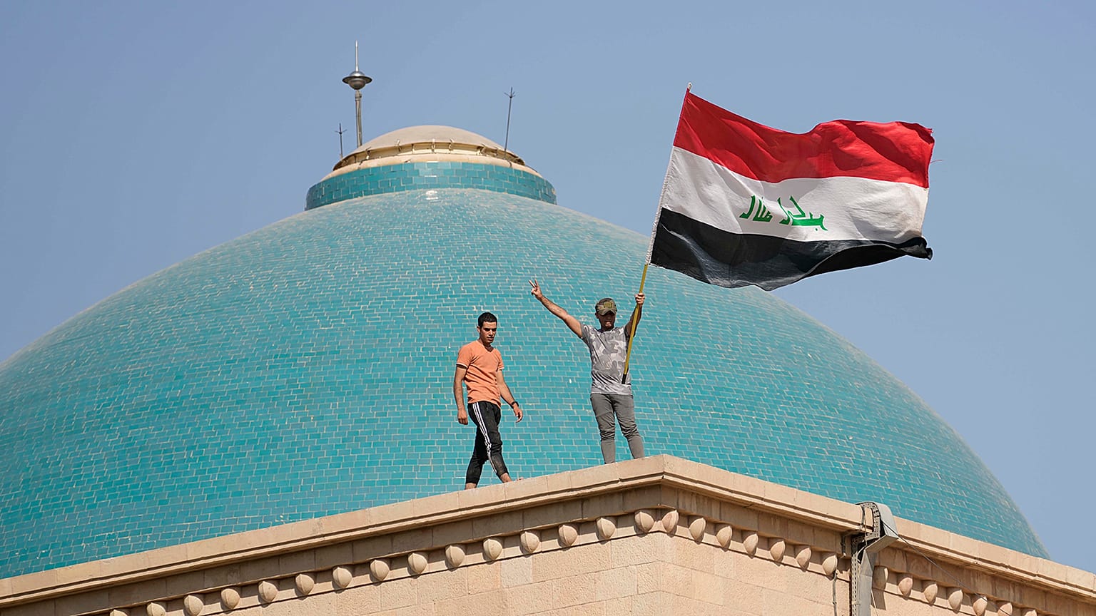 Supporters of Shiite cleric Muqtada al-Sadr wave a national flag from the roof of the Government Palace during a demonstration in Baghdad, 29 August 2022