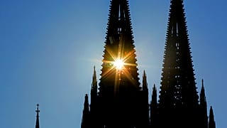 Die Sonne scheint durch einen der zwei Türme des Kölner Doms.