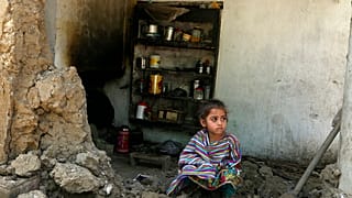 Ein Mädchen sitzt in den Trümmern ihres Zuhauses in Charsadda, Pakistan