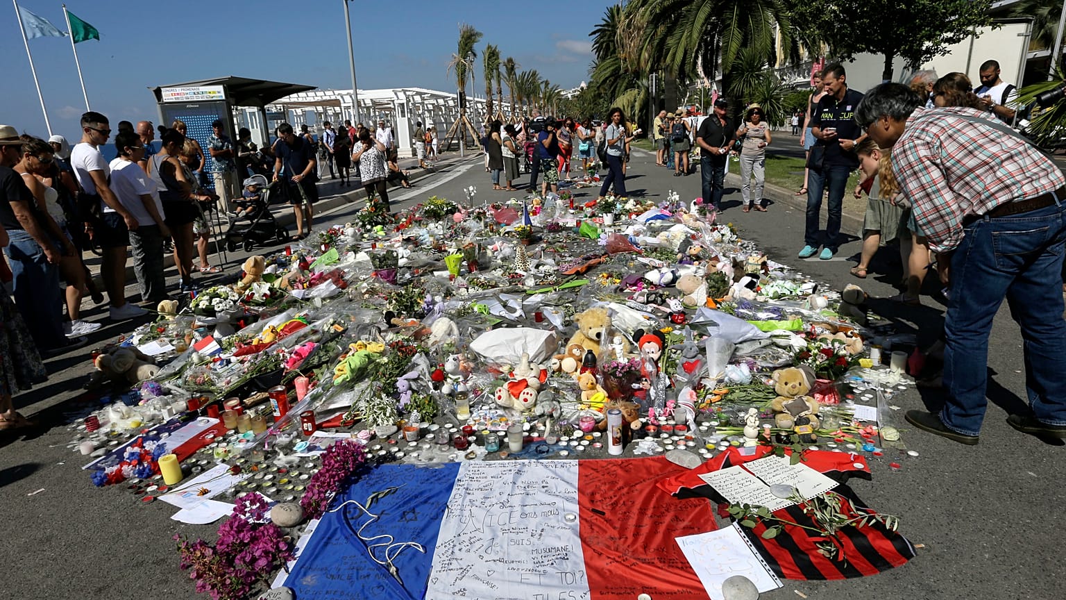 La gente mira las flores colocadas en el Paseo de los Ingleses en el lugar del atentado con un camión
