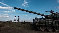 Sur cette photo d'archive prise le 11 décembre 2020, des jeunes marchent à côté d'un tank abandonné et détruit au sud de la ville de Mehoni, en Éthiopie.