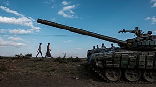 Sur cette photo d'archive prise le 11 décembre 2020, des jeunes marchent à côté d'un tank abandonné et détruit au sud de la ville de Mehoni, en Éthiopie.