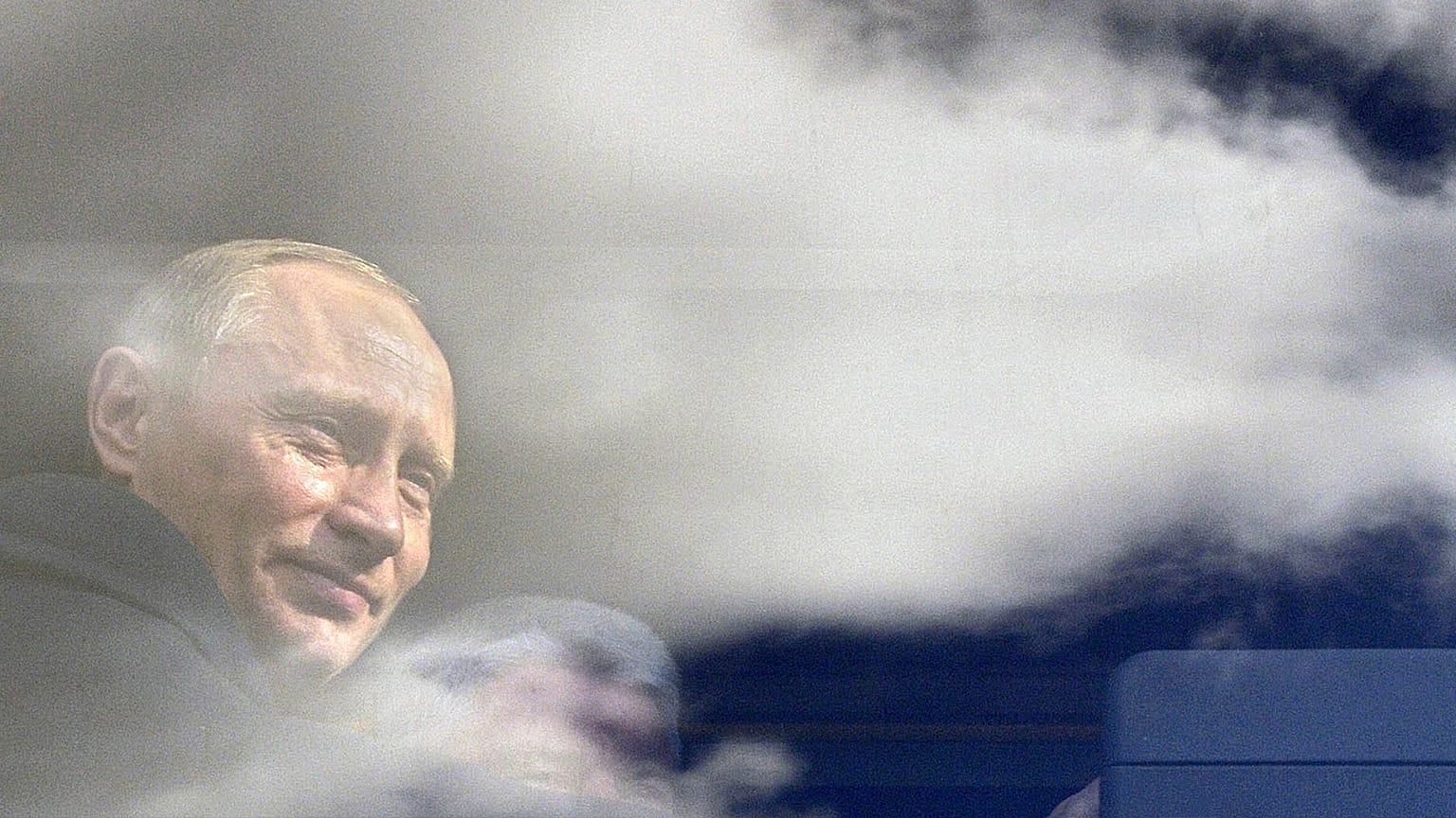 Russian President Vladimir Putin seen through a bus window, which reflects sky and clouds, during his visit to Kaliningrad in July 2005