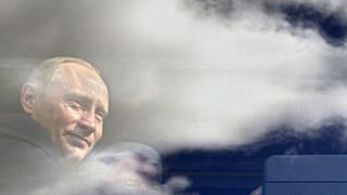 Russian President Vladimir Putin seen through a bus window, which reflects sky and clouds, during his visit to Kaliningrad in July 2005