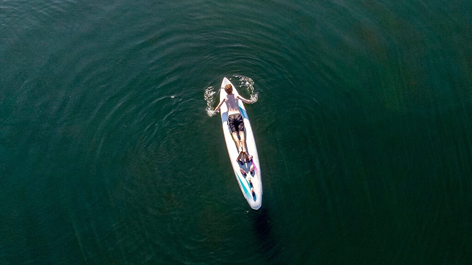 A man paddles on a surf board 