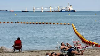 Playa de Gibraltar, con las tareas de extracción de combustible del buque accidentado al fondo.