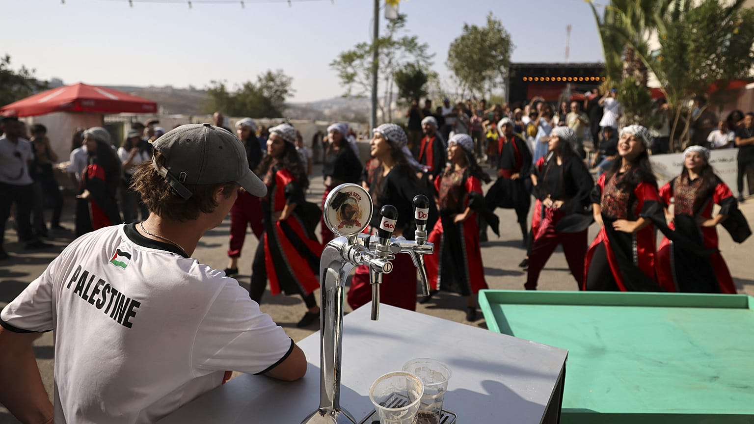 زائر يشاهد عرض راقصين فلسطينيين خلال مهرجان أكتوبر السنوي للبيرة في قرية طيبة في الضفة الغربية المحتلة. 2022/09/02