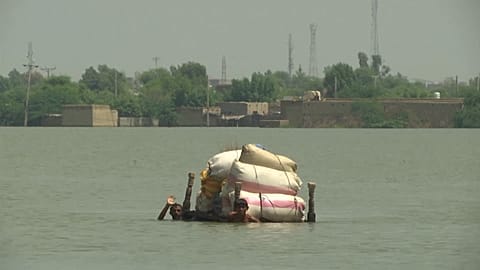 Villagers carrying their belongings through floodwater
