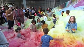 Attendees at an art insulation in London play in an island of foam.