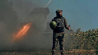 A Ukrainian soldier holds a watermelon and thumbs up as a rocket launch system fires in the font line in Donetsk region, eastern Ukraine, Saturday, Aug. 3, 2022.