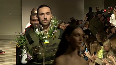 Model donning Bulletproof vest with flowers poking out 
