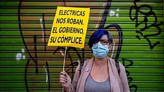 A woman holds a sign reading "The electric companies rob us. The government their accomplice" as she protests the rise in electricity prices in Madrid, Spain, Oct. 6, 2021.