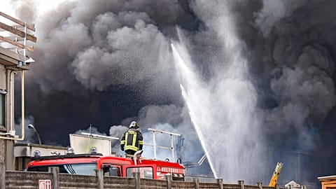 Firefighters spray water as black smoke comes out of chemical plant NitrolChimica.