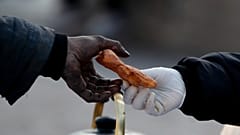A woman working for a social organization hands a snack to a homeless man on 9 de Julio Avenue in Buenos Aires, Argentina, Monday, May 31, 2021