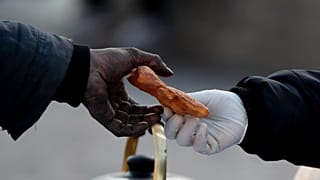 A woman working for a social organization hands a snack to a homeless man on 9 de Julio Avenue in Buenos Aires, Argentina, Monday, May 31, 2021