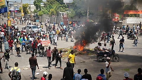 People walk around burning tires set up by protesters during a protest 
