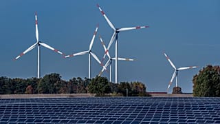 Wind turbines turn behind a solar farm in Rapshagen, Germany, Oct. 28, 2021.