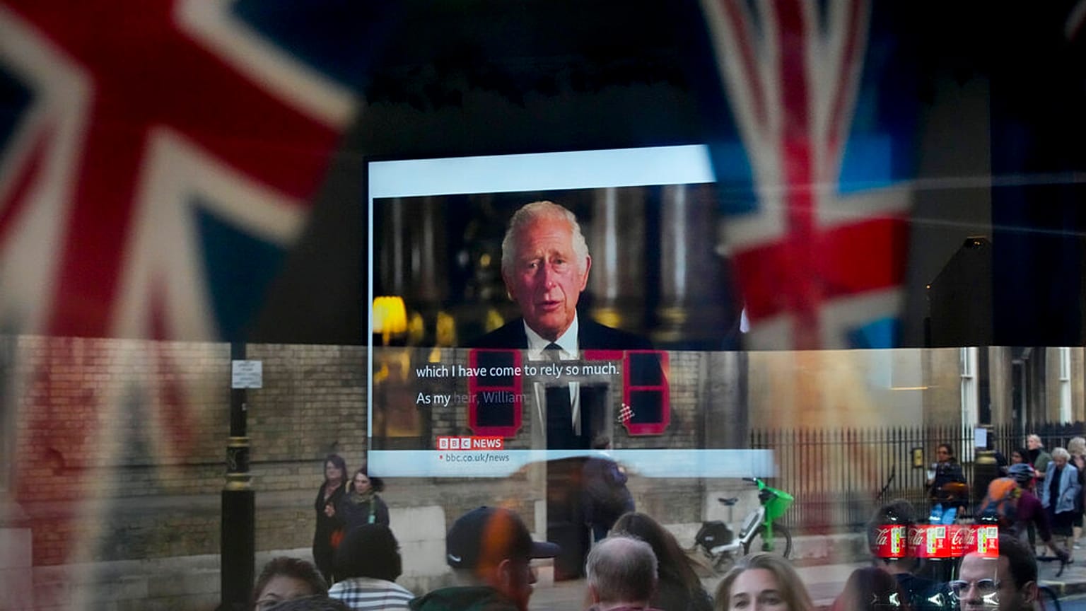 Des passants tentent d'apercevoir le discours télévisé du nouveau roi Charles III alors qu'ils passent devant un pub à Londres, vendredi 9 septembre 2022
