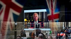 Des passants tentent d'apercevoir le discours télévisé du nouveau roi Charles III alors qu'ils passent devant un pub à Londres, vendredi 9 septembre 2022