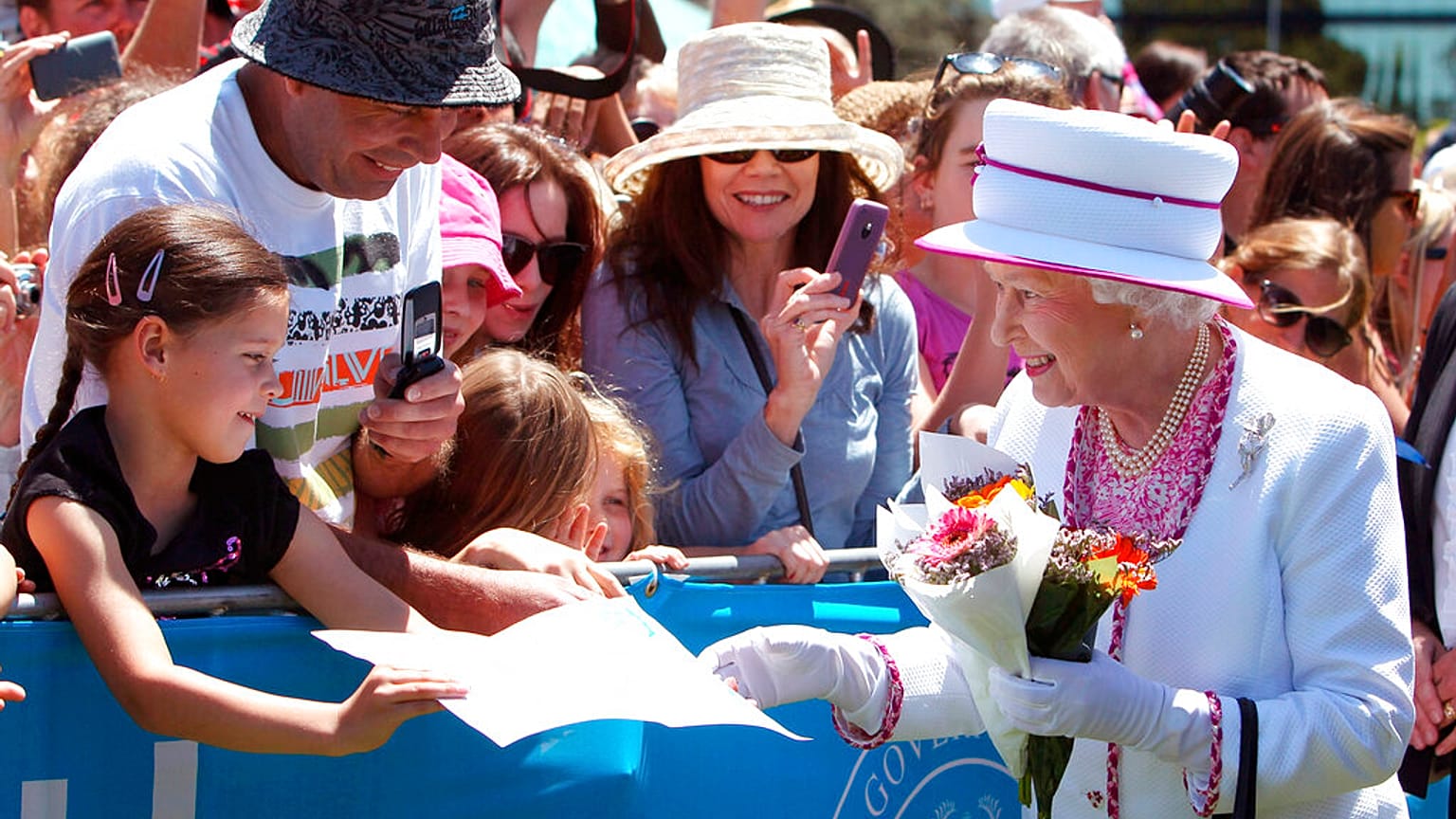Una niña regala a la Reina Isabel II una foto mientras camina entre la multitud