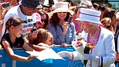 Una niña regala a la Reina Isabel II una foto mientras camina entre la multitud