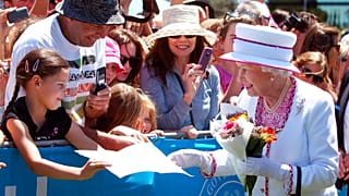 Una niña regala a la Reina Isabel II una foto mientras camina entre la multitud