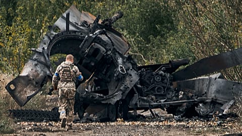 A Ukrainian soldier passes by a Russian tank damaged in a battle in a just freed territory on the road to Balakleya in the Kharkiv region, 11 September 2022