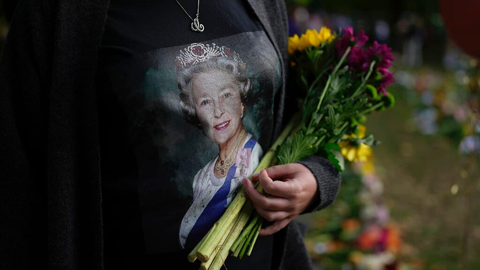 Une femme tient des fleurs au mémorial de Green Park, près du palais de Buckingham à Londres, dimanche 11 septembre 2022. 