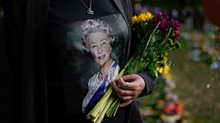 Une femme tient des fleurs au mémorial de Green Park, près du palais de Buckingham à Londres, dimanche 11 septembre 2022.