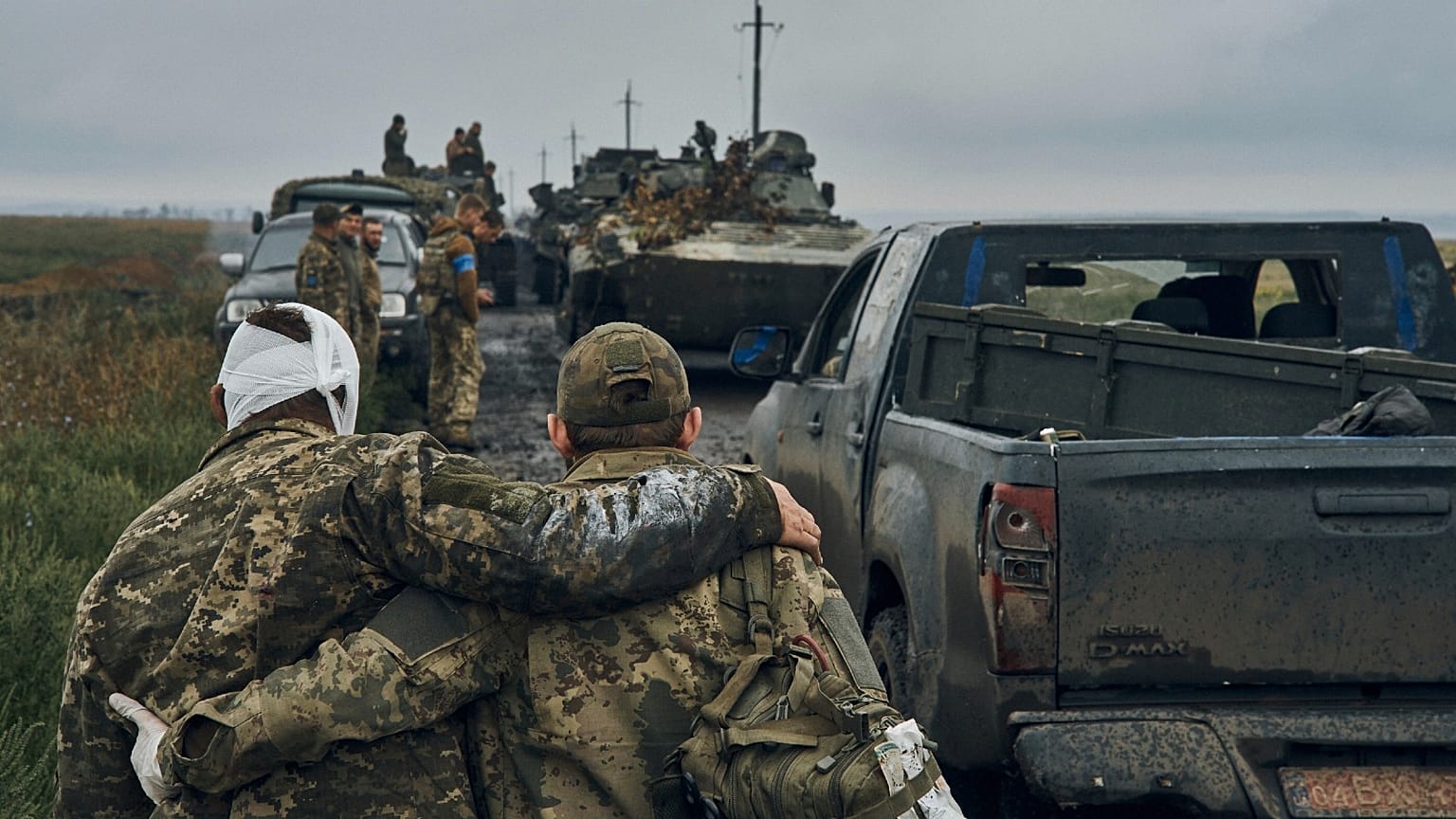 A Ukrainian soldier helps a wounded fellow soldier on the road in the freed territory in the Kharkiv region, Ukraine, Monday, Sept. 12, 2022.