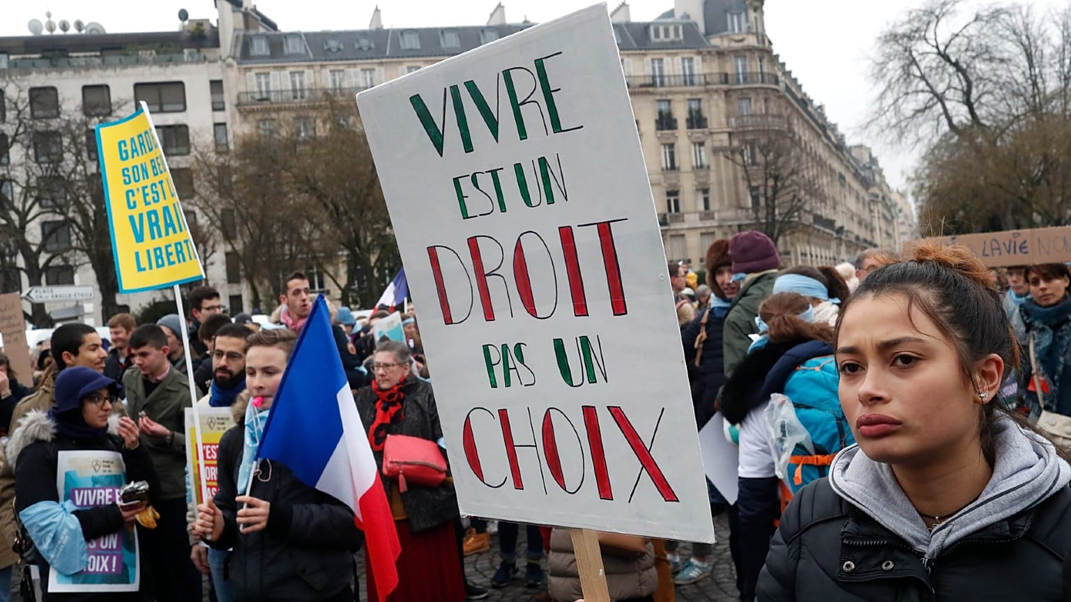 A woman holds a placard reading "Living is right, not a choice" during a demonstration against abortion and euthanasia in Paris