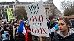 A woman holds a placard reading "Living is right, not a choice" during a demonstration against abortion and euthanasia in Paris