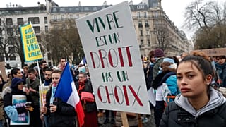 A woman holds a placard reading "Living is right, not a choice" during a demonstration against abortion and euthanasia in Paris