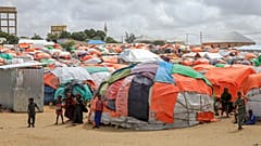 Somali children who fled drought-stricken areas stand by their makeshift shelters at a camp for the displaced on the outskirts of Mogadishu, Somalia Saturday, Sept. 3, 2022. 