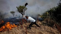 A local resident fights a forest fire with a shovel during a wildfire in Tabara, north-west Spain, July 19, 2022