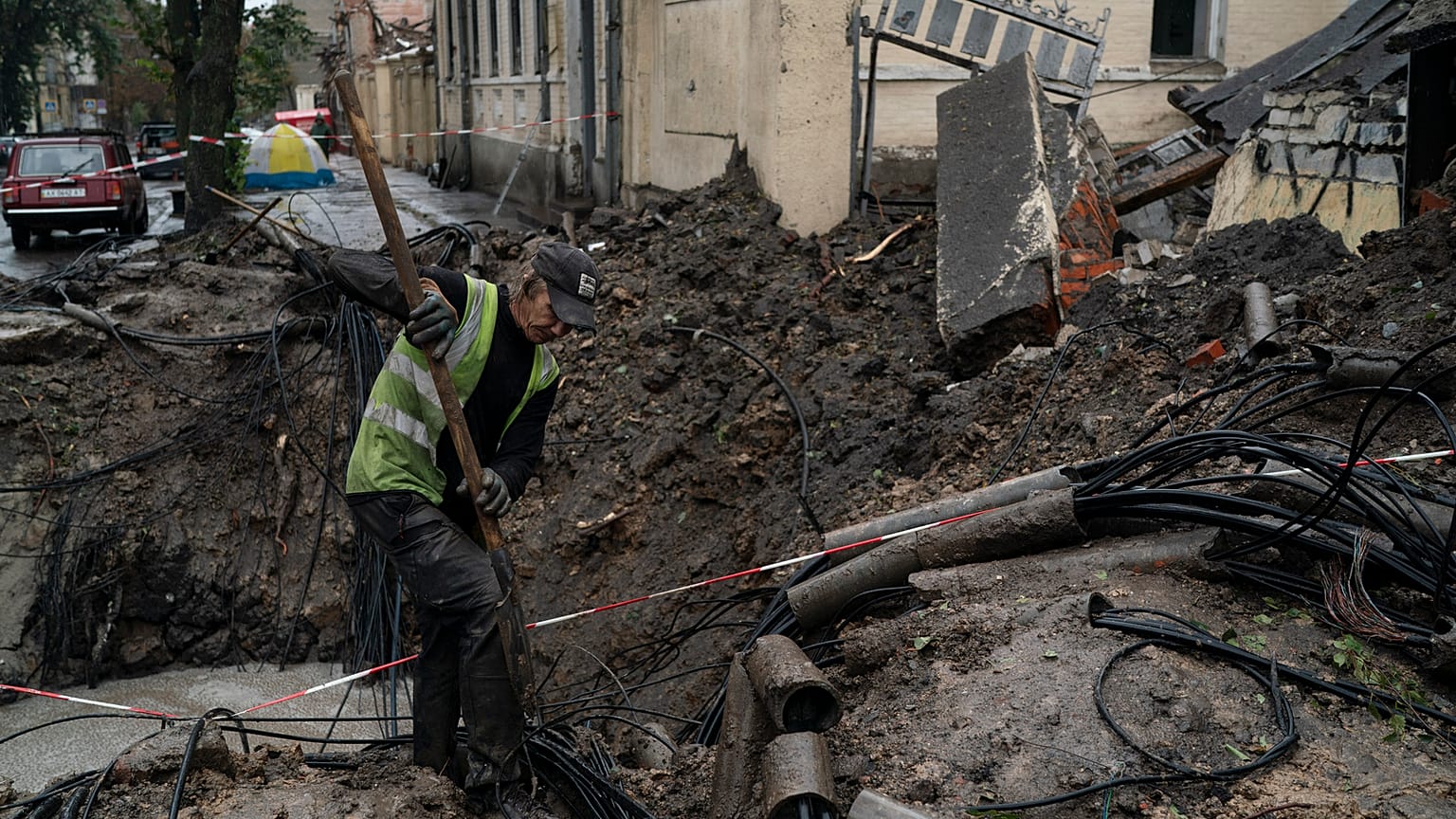 A man works next to a crater created by an explosion to fix the internet cables after a Russian attack in downtown, Kharkiv, Ukraine, Friday, 16 September 2022. 