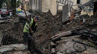 A man works next to a crater created by an explosion to fix the internet cables after a Russian attack in downtown, Kharkiv, Ukraine, Friday, 16 September 2022. 