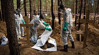 Работники МЧС закрывают полиэтиленовый пакет с телом мирного жителя во время эксгумации под Изюмом, 17.09.2022