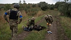 Украинские военнослужащие осматривают тело украинского солдата на отвоеванном участке у границы с Россией в Харьковской области, 17.09.2022