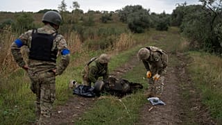Украинские военнослужащие осматривают тело украинского солдата на отвоеванном участке у границы с Россией в Харьковской области, 17.09.2022