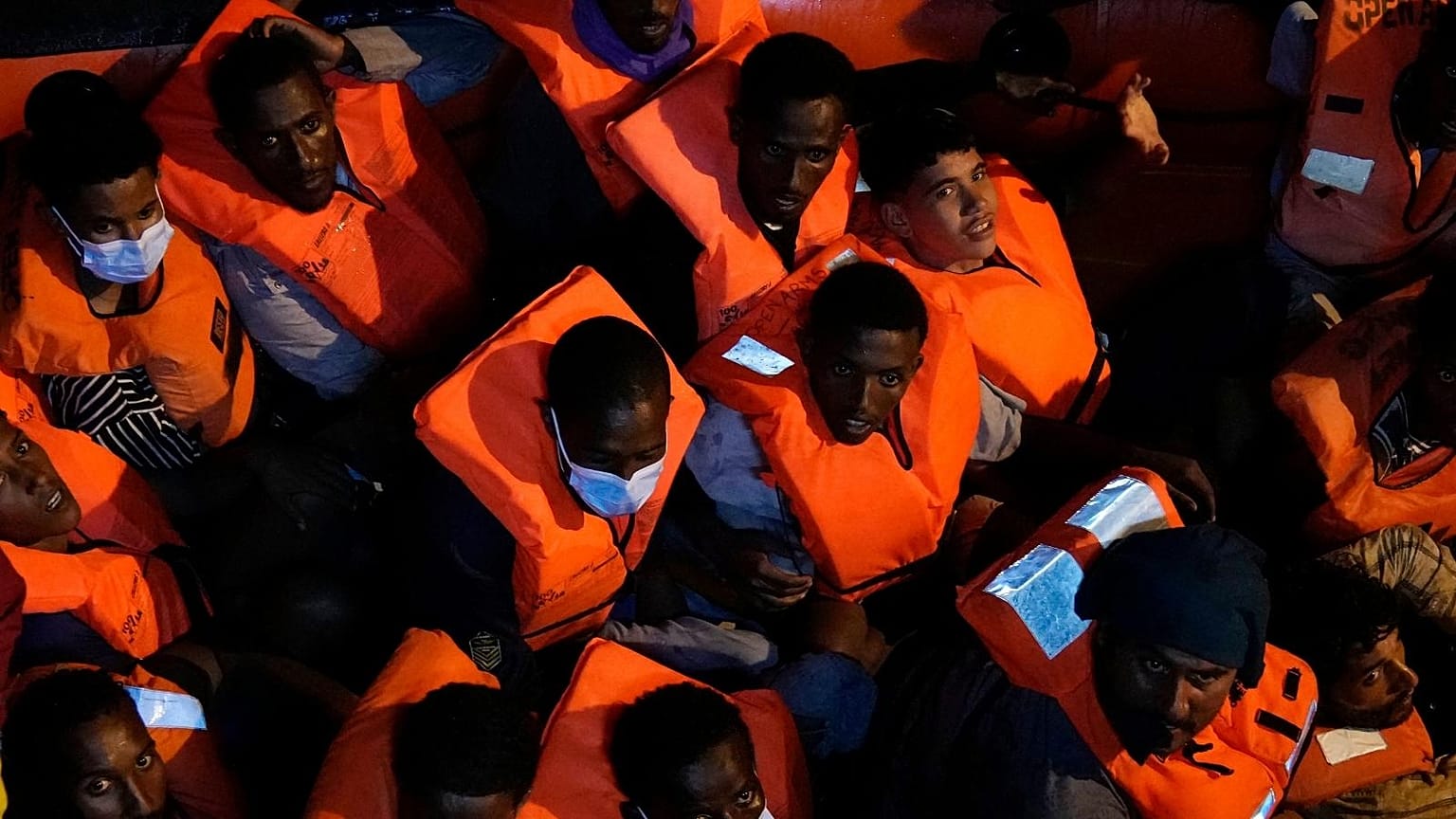 Migrants rescued by the Spanish NGO Open Arms in the Mediterranean sea huddle in a boat early Sunday, Sept. 18, 2022.