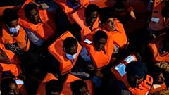 Migrants rescued by the Spanish NGO Open Arms in the Mediterranean sea huddle in a boat early Sunday, Sept. 18, 2022.