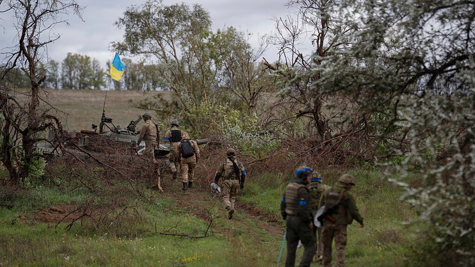 Ukrainian national guard servicemen walk next to a damaged Russian tank